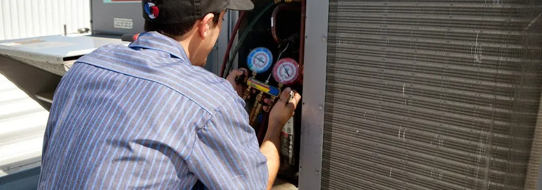 HVAC technician servicing a condenser unit in Pepperell