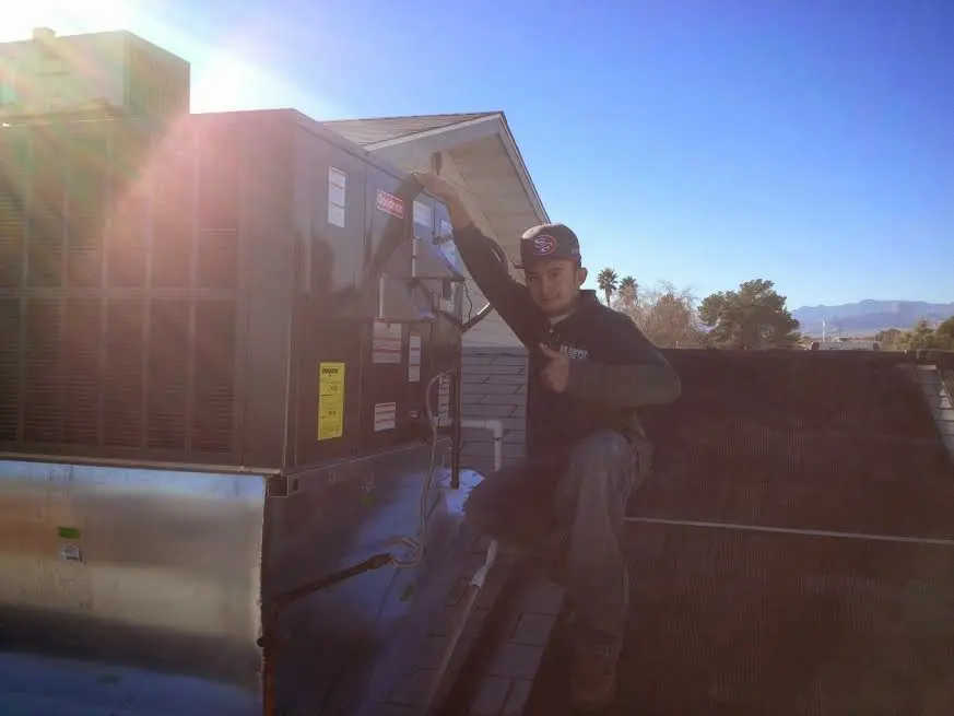 HVAC technician performing Boiler Repair on a rooftop unit in Pepperell